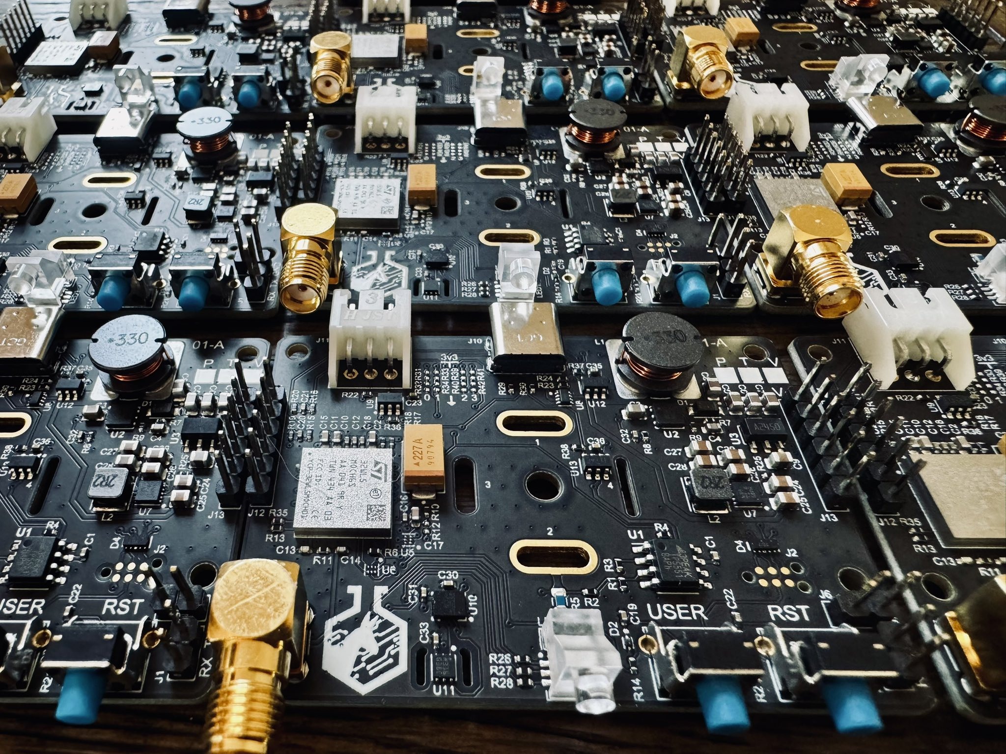 A row of custom Barkeep circuit boards populated with surface-mount components, gold SMA antenna connectors, and a wireless module.